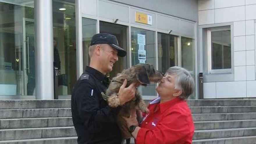 Un agente policial devuelve la perra a la víctima. / la opinión