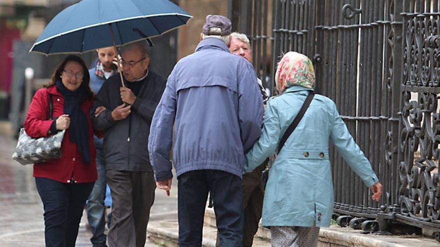 Turistas y malagueños pasean bajo la lluvia junto a la Catedral, este pasado martes.