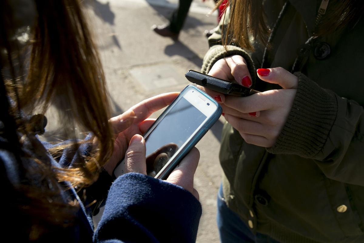 Jóvenes utilizando el móvil a la salida de su instituto.