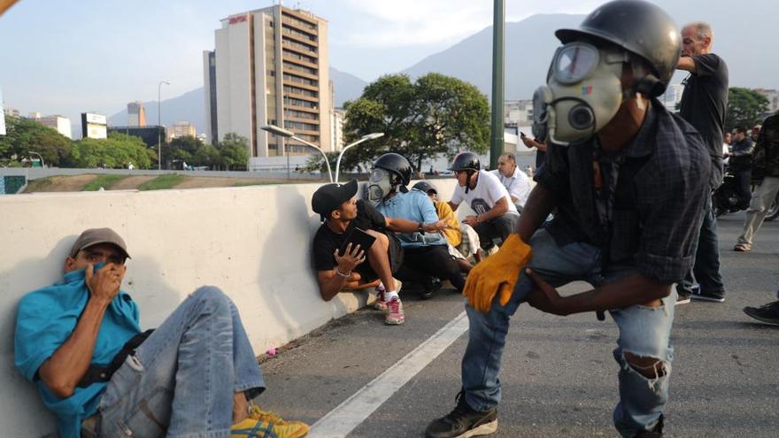 Simpatizantes de Guaidó se protegen de las bombas lacrimógenas. // EFE