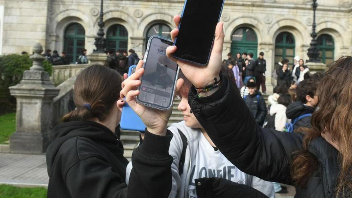 Jóvenes con el móvil a la salida de un instituto coruñés.