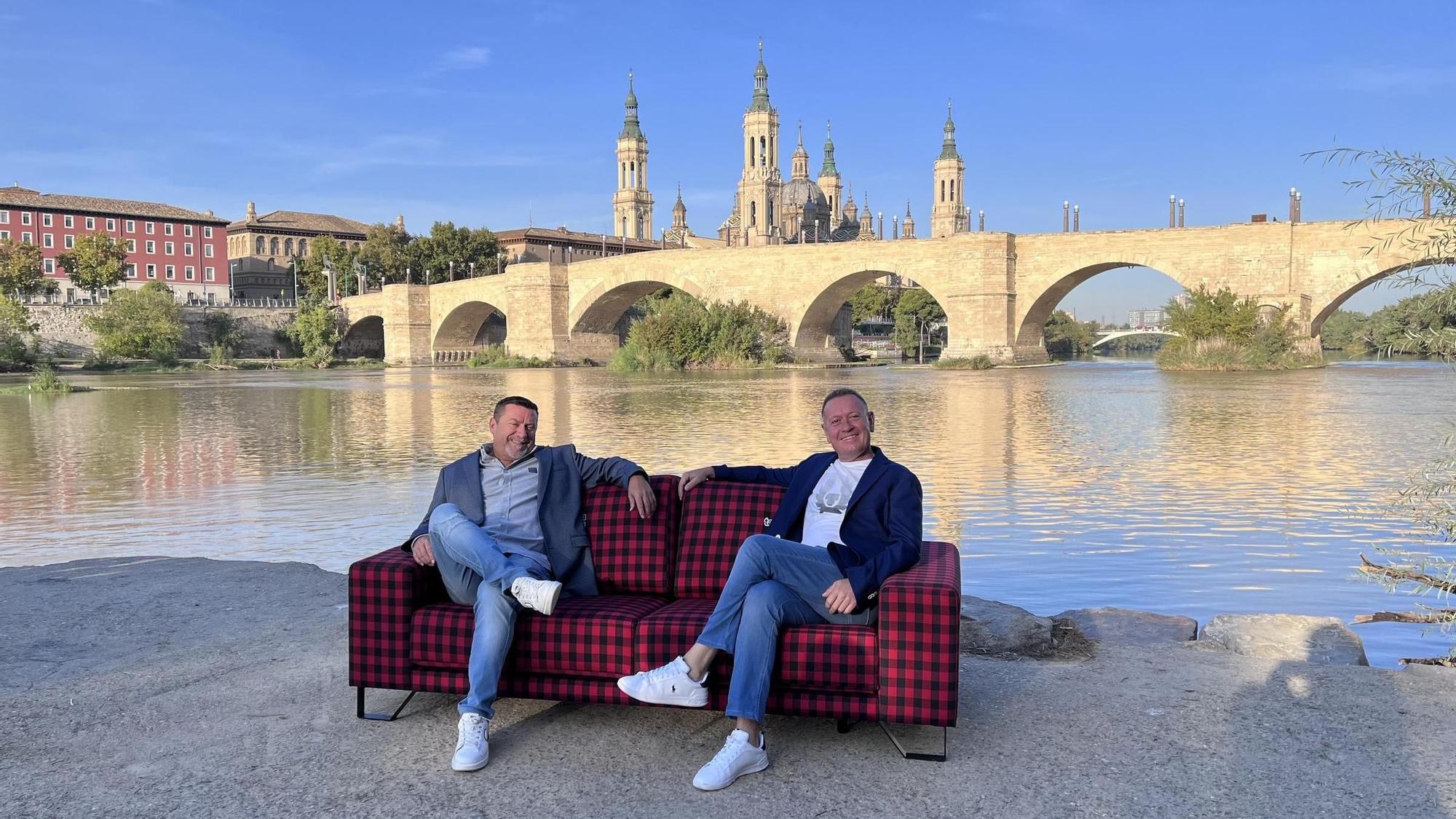 Antonio Torres y Jesús Galve, fundadores de Tapigrama, sentados en uno de sus sofás personalizados a orillas del Ebro en Zaragoza.