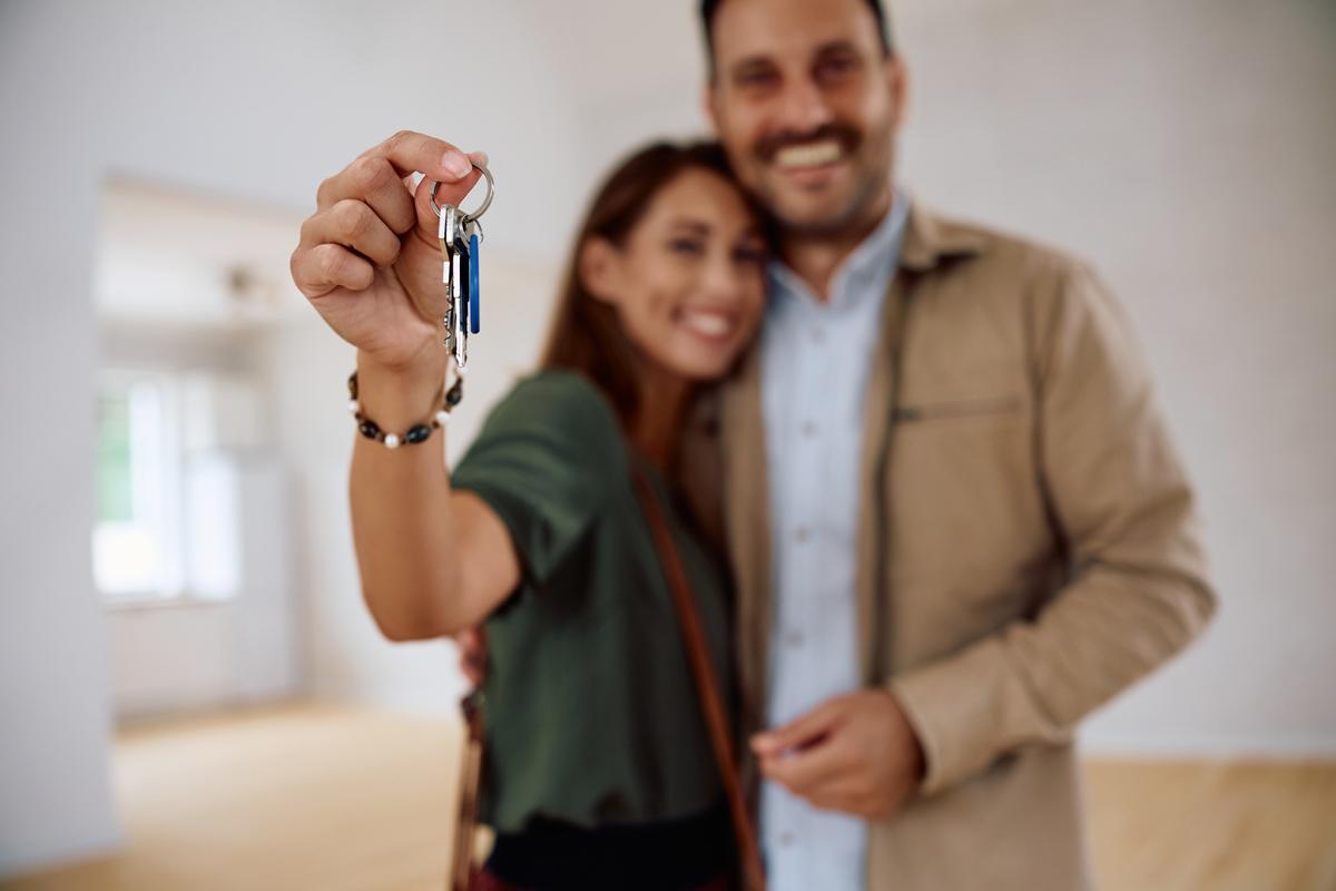 Una pareja orgullos muestra las llaves de su casa.