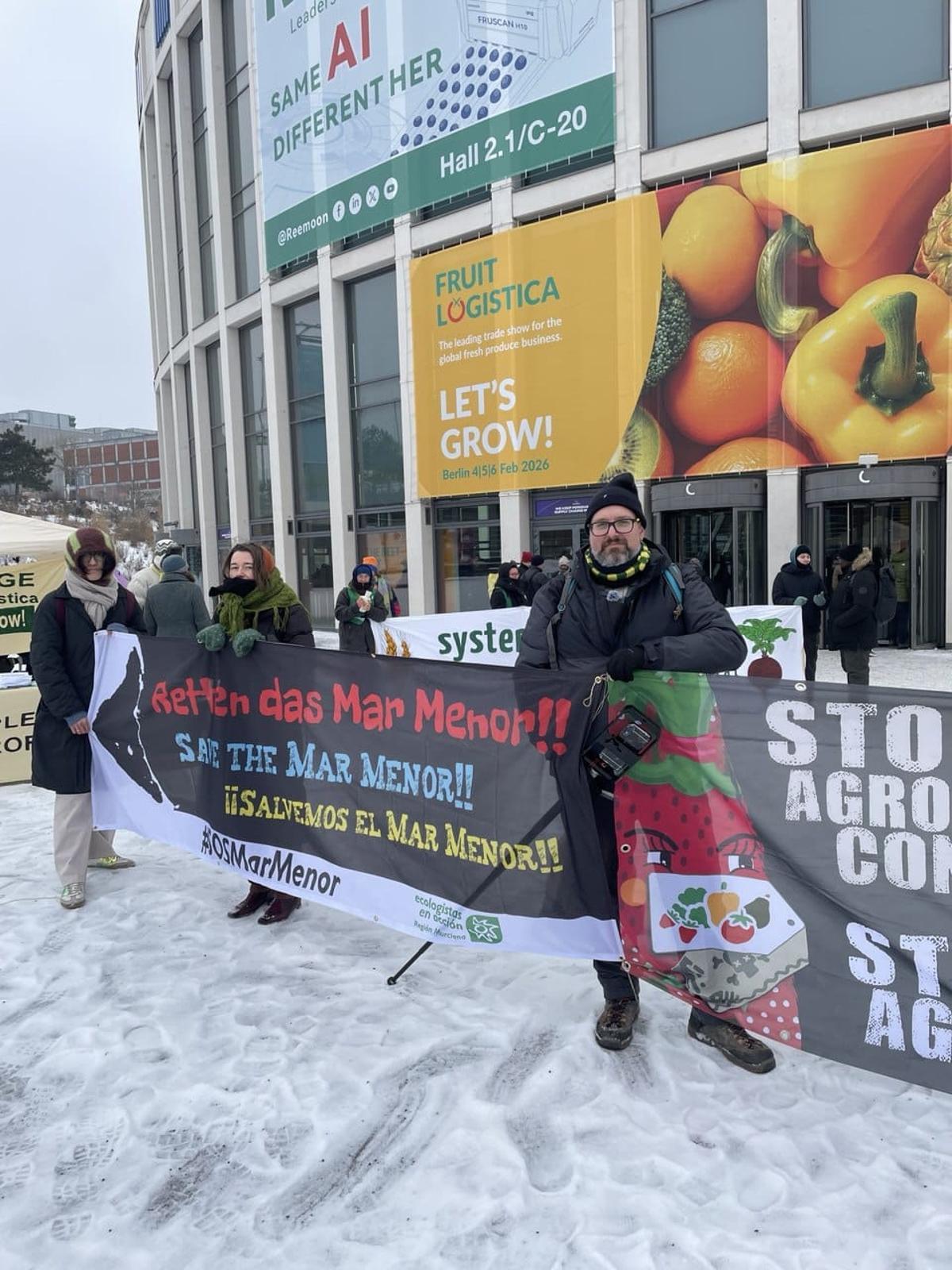 El portavoz murciano de Ecologistas en Acción, Pedro Luengo, sostiene un cartel con el lema 'Salvemos el Mar Menor' en uno de los accesos a la feeria Fruit Logistica de Berlín.