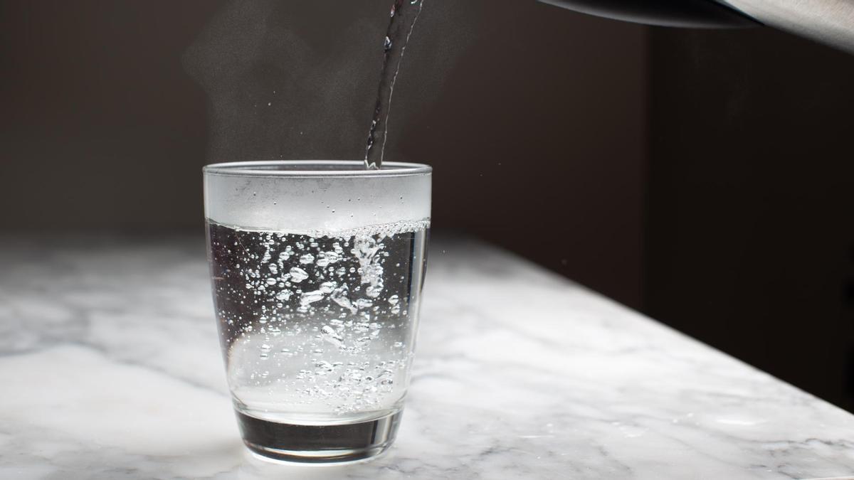 Una persona sirve un vaso de agua.