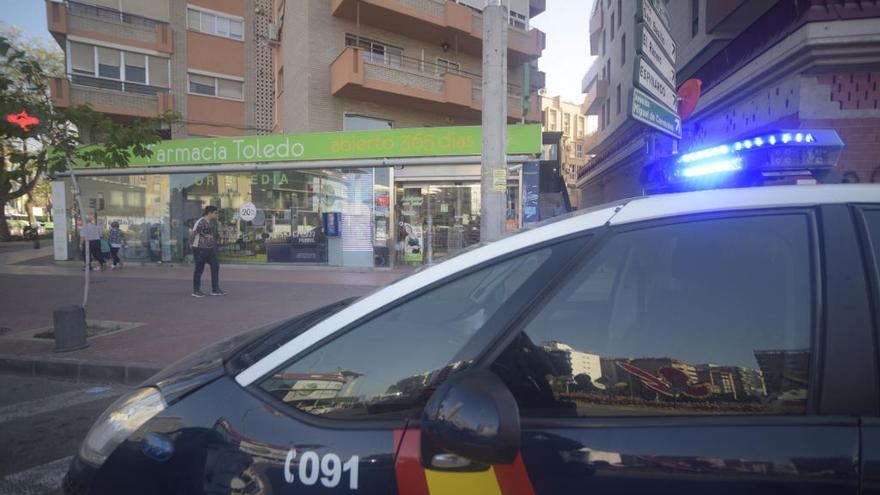 Un coche de la Policía Nacional, frente a la primera farmacia atracada, esta mañana.