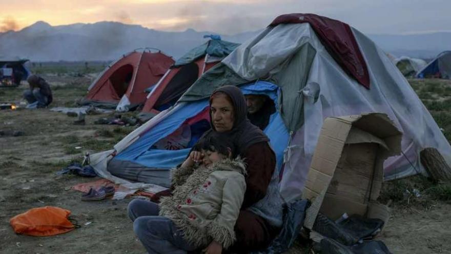 Una mujer y un niño, sentados delante de su tienda en el campo de refugiados de Idomeni, en la frontera de Grecia y Macedonia. // Reuters