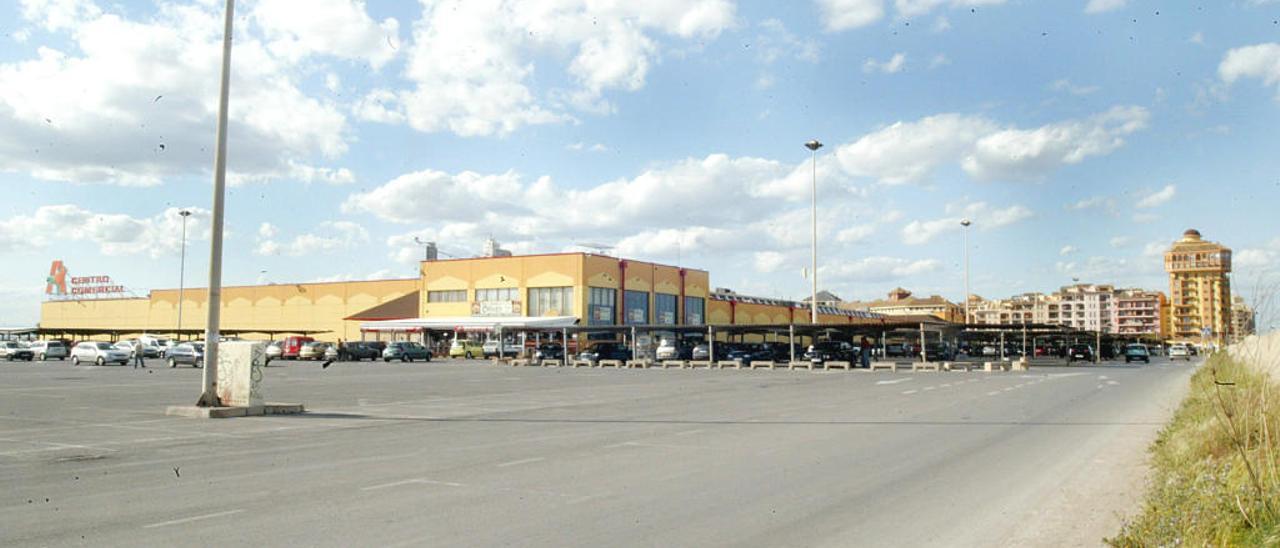 Aparcamiento de la zona comercial de Port Saplaya, con los bloques de apartamentos al fondo.