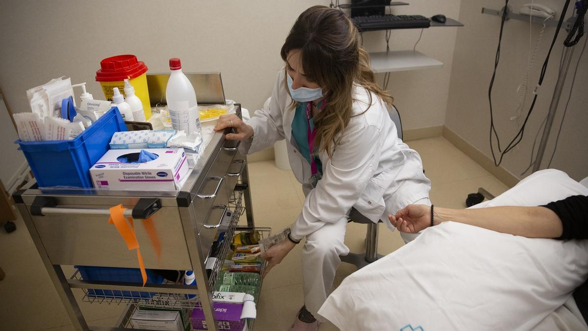 Una sanitaria trata a una paciente oncológica en un hospital catalán.