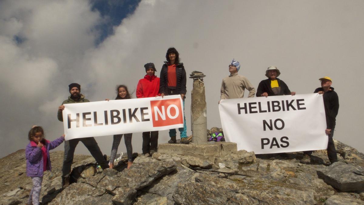 Los participantes en la subida a Punta Suelza, ayer, despliegan pancartas contra el helibike en la cima de la montaña.