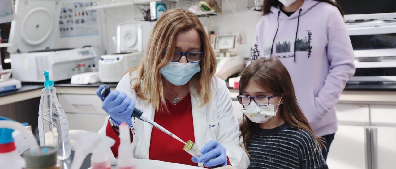 Una científica muestra su trabajo a sus hijas en su laboratorio.