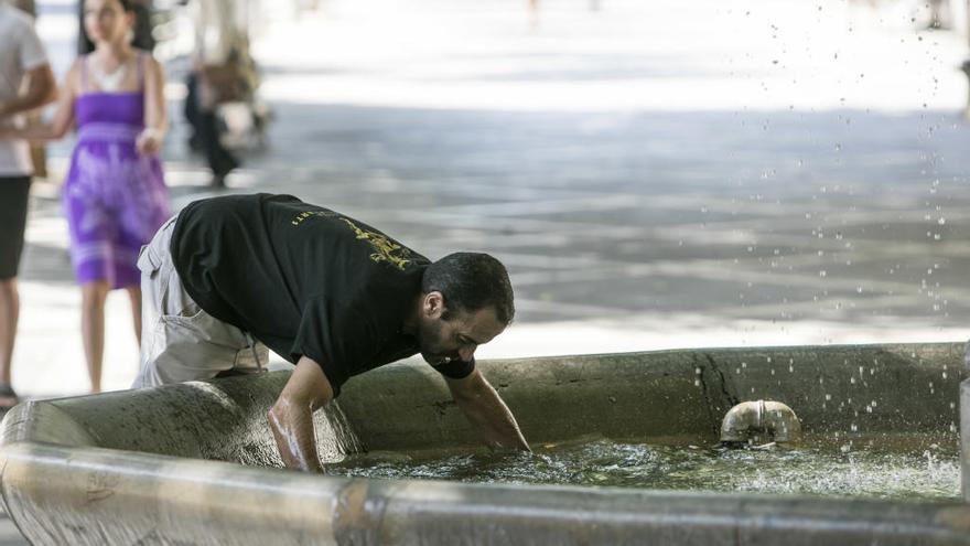 Un hombre se refresca en una fuente de Palma