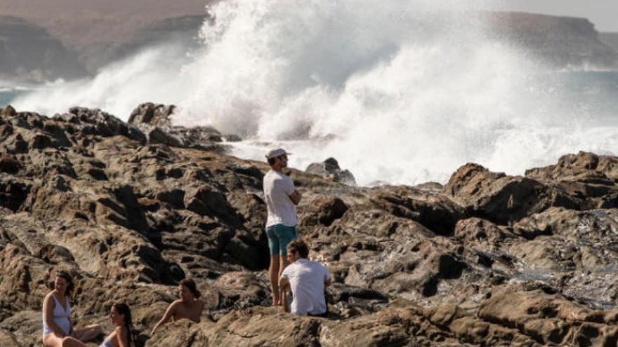 Unas personas observan la fuerza de las olas en la playa del Valle.