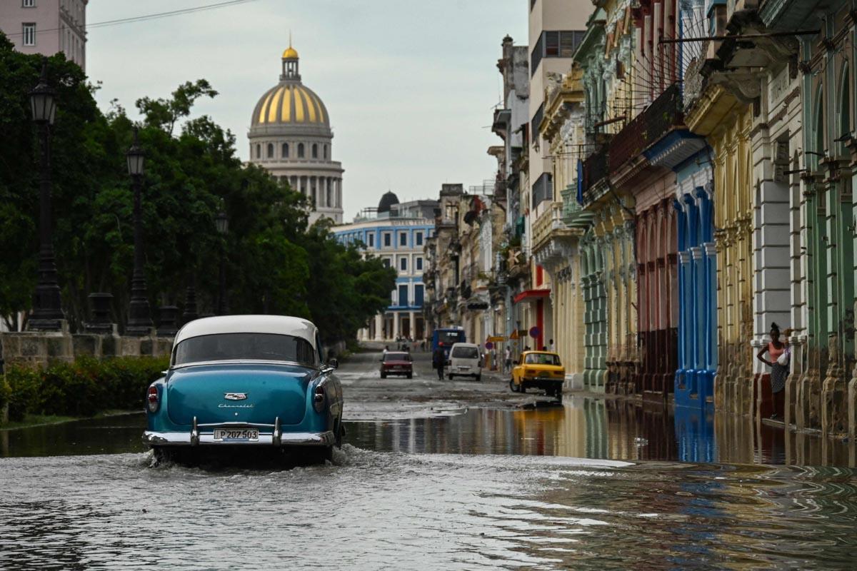 Un viejo automóvil estadounidense transita por una calle inundada de La Habana, tras el paso de Ian.