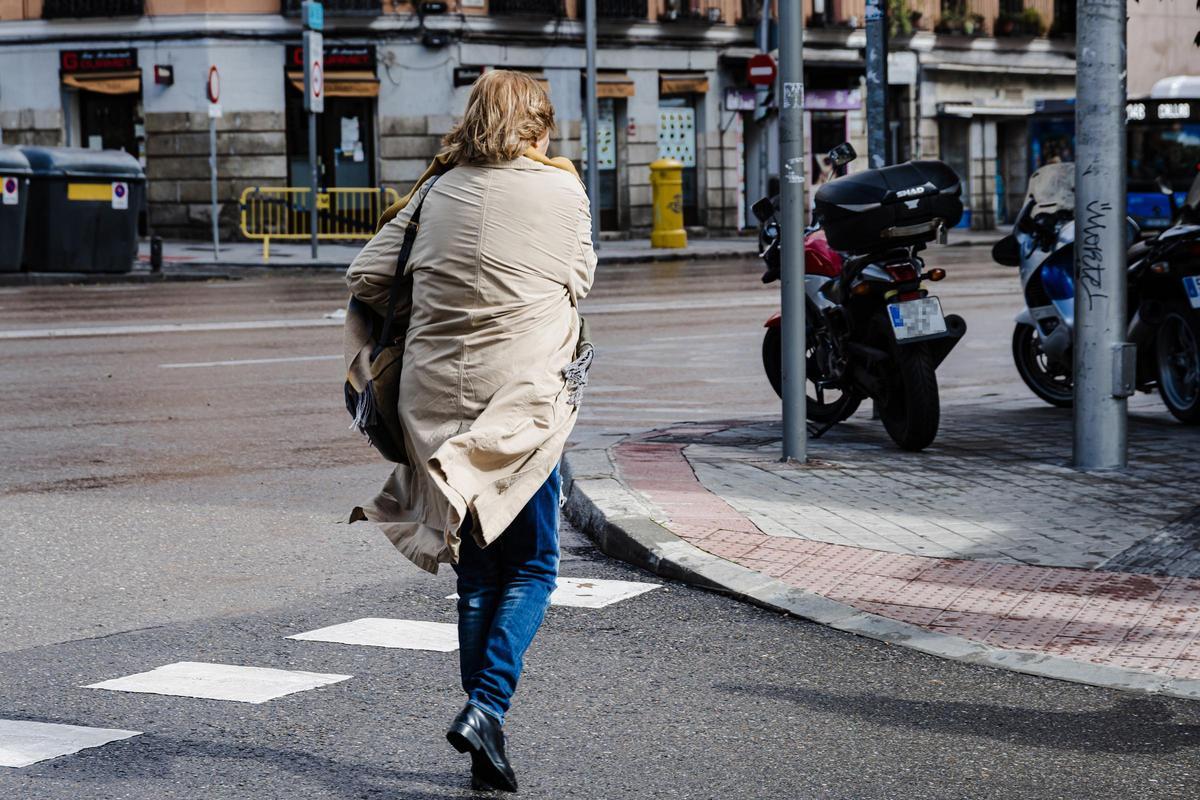 Una mujer con el pelo y la chaqueta movidos por el viento en Madrid.