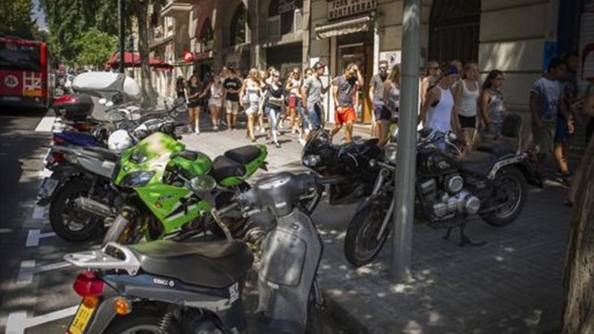 Motos aparcadas en el nuevo espacio de la calzada y otras en la acera con turistas al lado, ayer, en Marina.