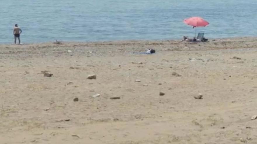 Vecinos se bañan y toman el sol en una playa con piedras en San Pedro Alcántara.