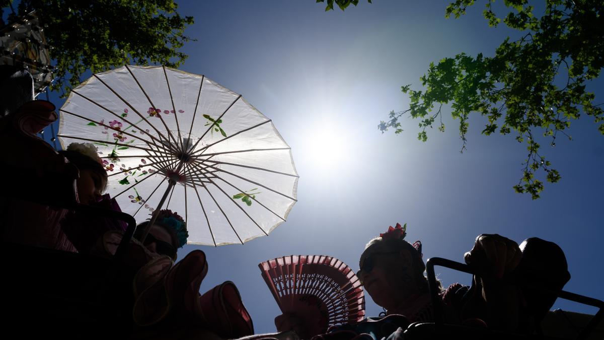 Un grupo de personas en un carruaje se protegen del sol en el Real de la Feria de Abril.