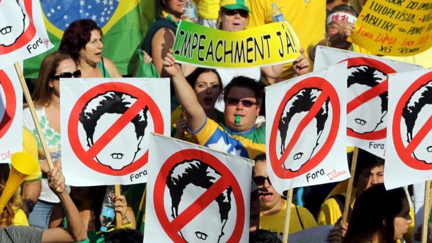 Manifestantes portan carteles contra la presidenta brasileña.