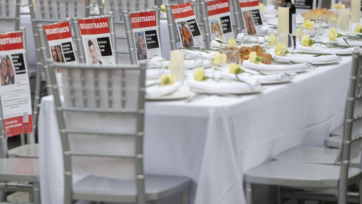 Una mesa con 241 sillas vacías para simbolizar la espera por el regreso de los rehenes capturados por Hamás, frente al Congreso de los Diputados.