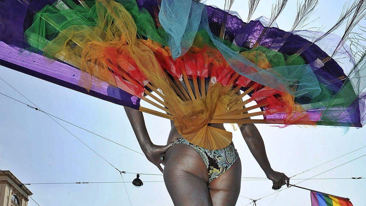 Una drag queen pasea con una bandera del orgullo.