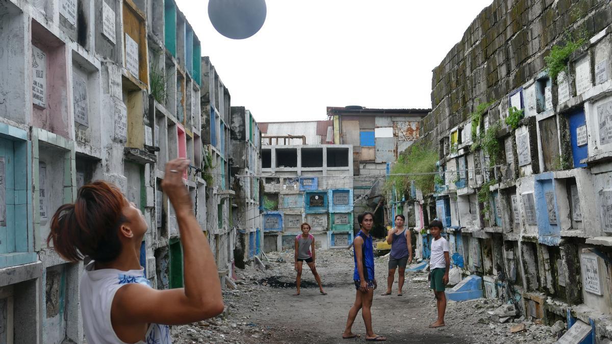 Un grupo de adolescentes juega al voleibol en un cementerio de Manila.