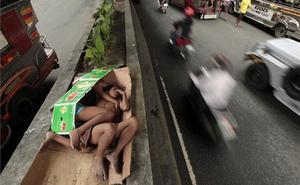 Dos nens dormen entre cartrons a la mitjana d’una carretera que travessa Pasay, al sud de Manila (Filipines).