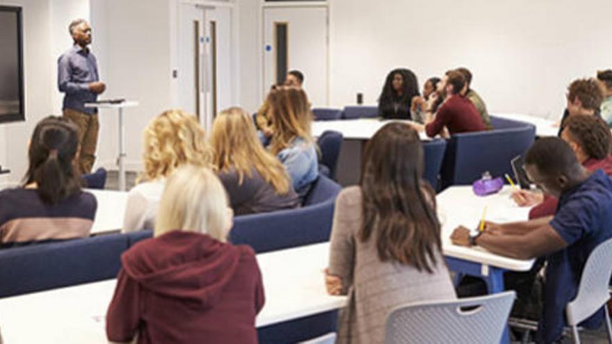 Varios alumnos atienden en un aula universitaria.