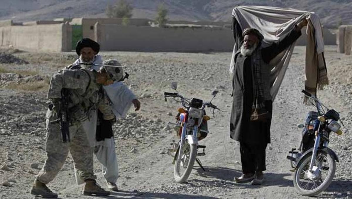 Un sargento estadounidense registra a dos hombres en busca de armas en un pueblo del distrito de Paniwai, en la provincia de Kandahar (Afganistán).