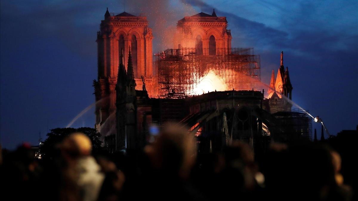 Decenas de personas observan las llamas en la catedral de París.