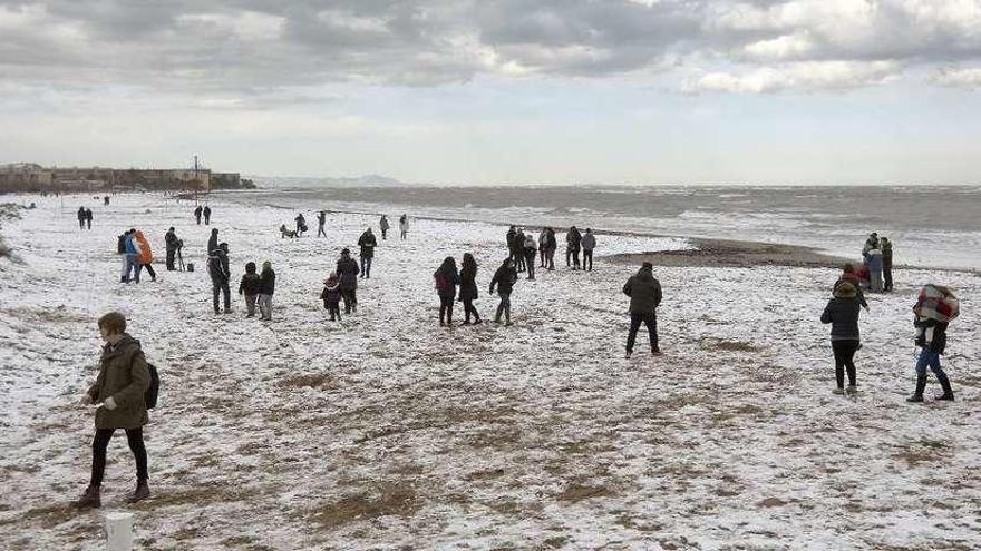 Curiosos pasean por una de las playas de Dénia que amaneció ayer cubierta de nieve. // Efe