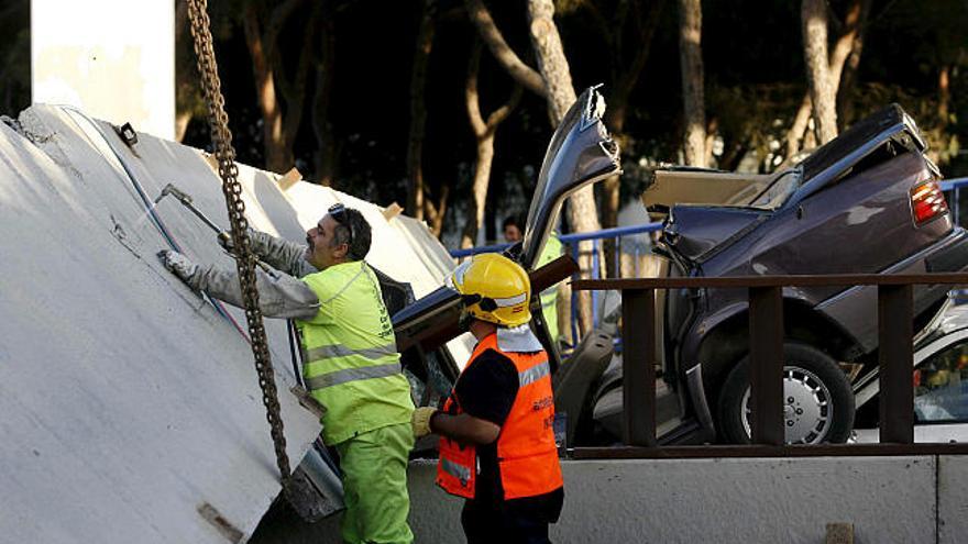 Un operario intenta retirar los restos de un paso peatonal elevado que se ha caido esta tarde sobre la autovía A-7, en la localidad malagueña de Mijas, hiriendo a seis personas personas, entre ellas a un niño de dos años.