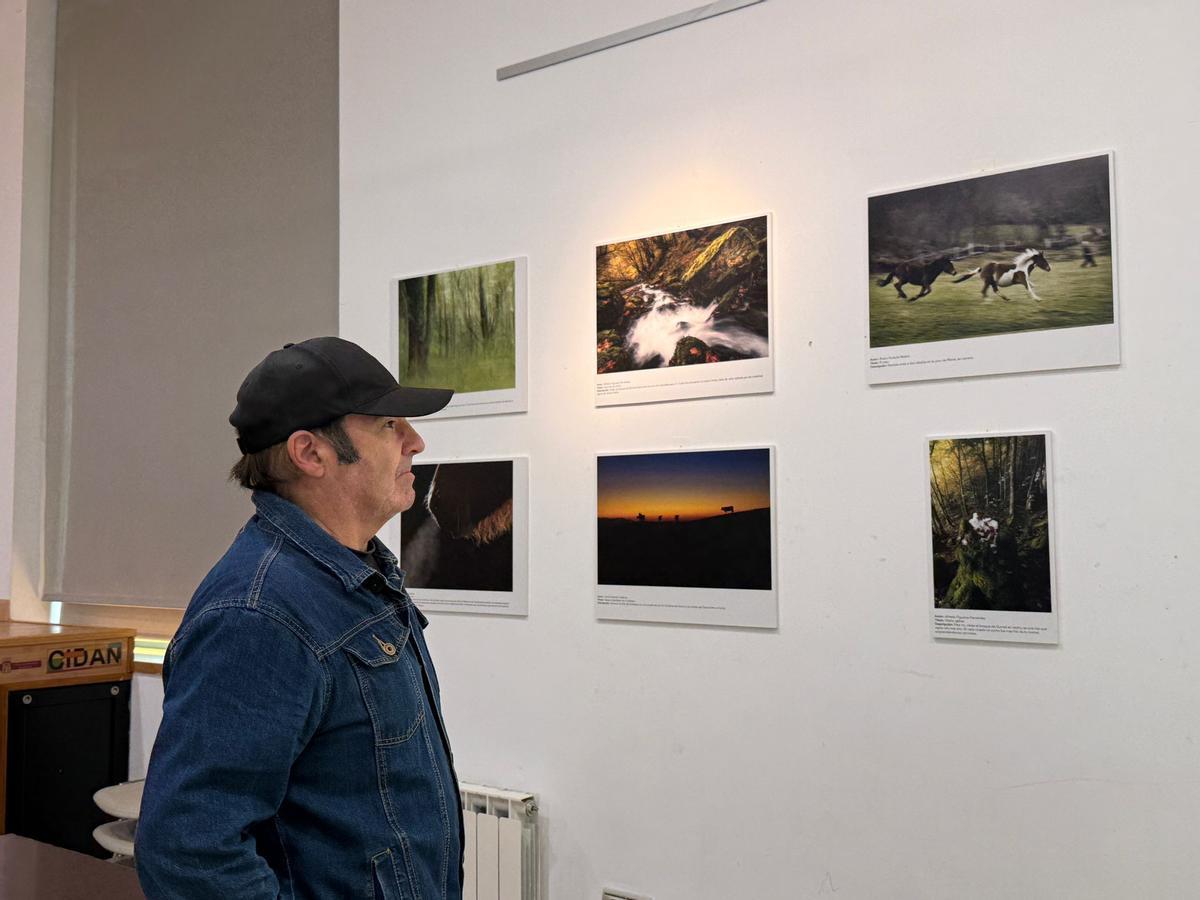 Jorge Suárez contemplando varias fotografías de la exposición.