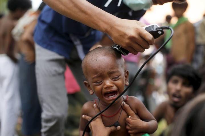 A Rohingya migrant child, who recently arrived in Indonesia by boat, cries as a volunteer cuts his hair inside a temporary compound for refugees in Aceh Timur regency