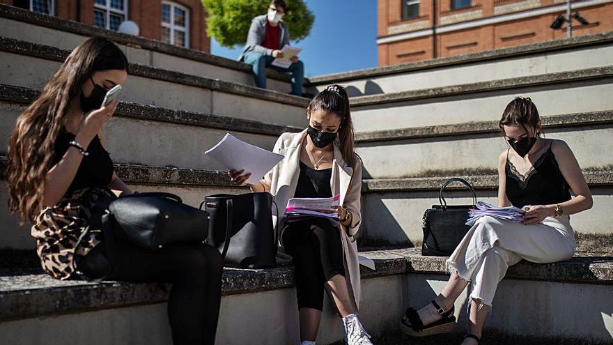 Tres estudiantes repasan sus apuntes antes de entrar en las pruebas de la EBAU.