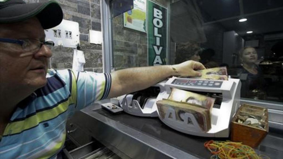 Un empleado de una oficina de cambio colombiana, en la frontera con Venezuela, cuenta billetes de 100 bolívares.