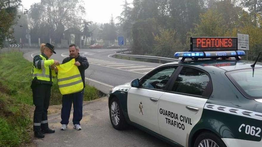 Una guardia civil entrega un chaleco a un peatón. // FdV