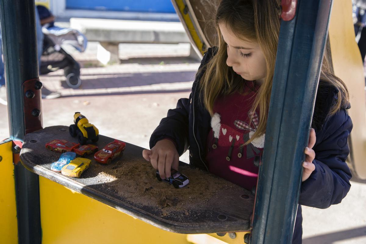 Una niña juega en un parque con coches.