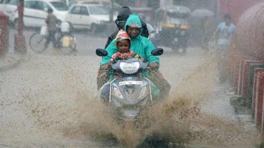Una familia circula en moto por la ciudad de Bhopal, anegada por las lluvias.