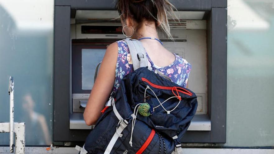 Una mujer saca dinero de un cajero autómatico.