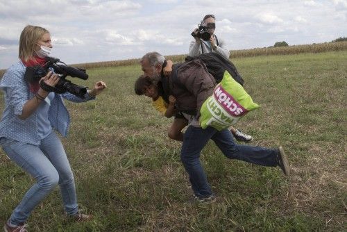 Una reportera húngara agrede a un refugiado que carga con su hijo.