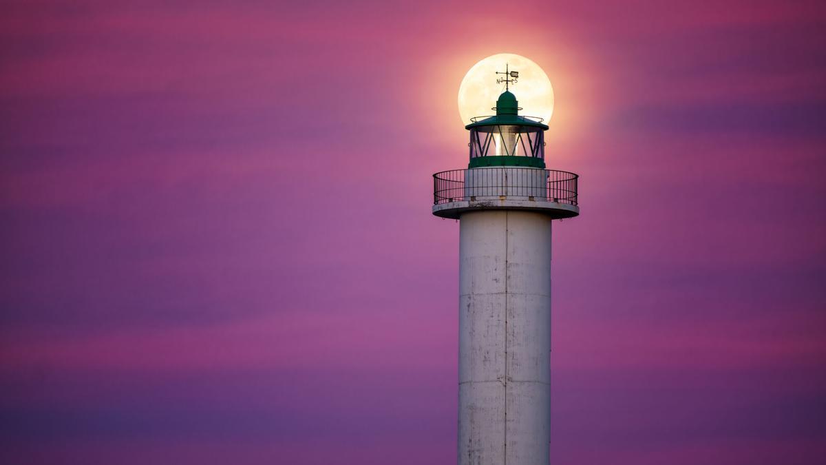 Primera luna  llena de 2025, denominada "Luna de Lobo", "posándose"  sobre el faro  de Lastres.