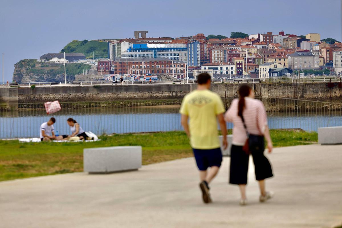 Gente paseando y tomando el sol en Naval Azul, con el Elogio del Horizonte al fondo.
