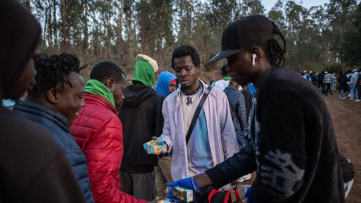 Algunos voluntarios ofrecen comida a migrantes en el centro de Las Raíces, en Tenerife.