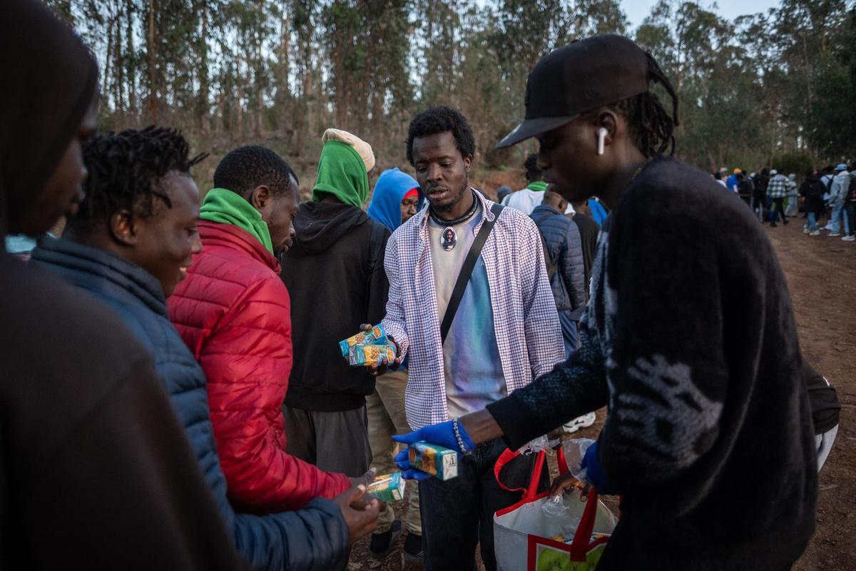 Algunos voluntarios ofrecen comida a migrantes en el centro de Las Raíces, en Tenerife.