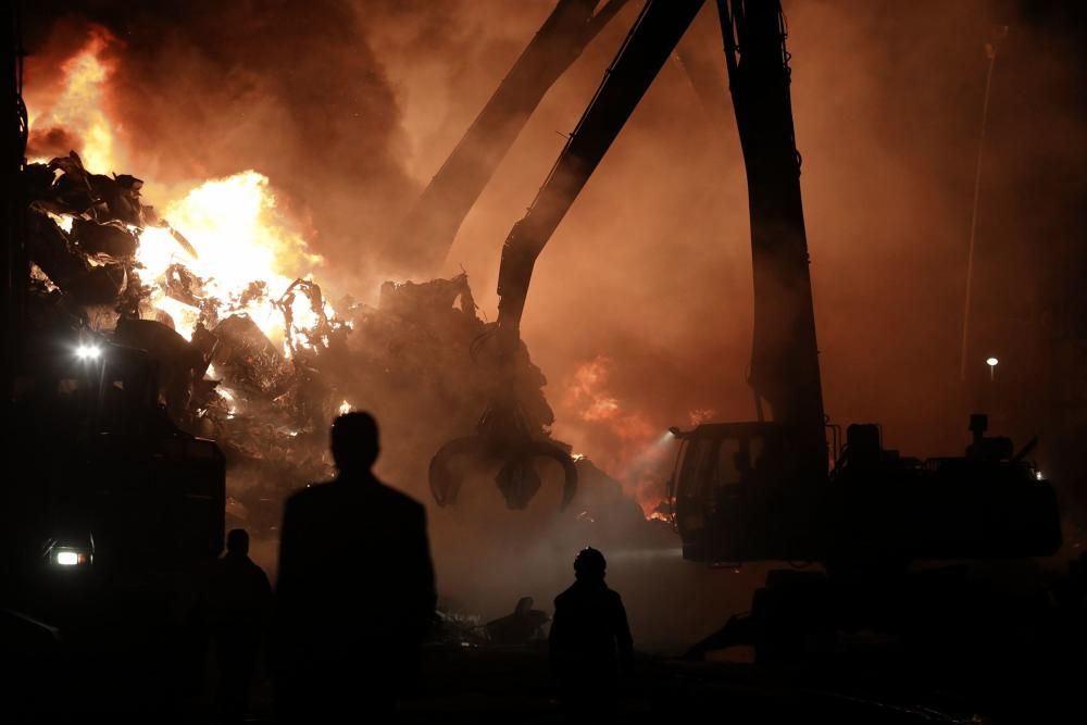 Labores de extinción del incendio de un desguace en Gijón