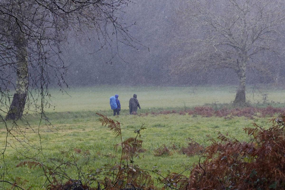 Dos peregrinos completan, bajo la lluvia, durante el mes de enero, un tramo del Camino de Santiago, en una jornada de temporal.
