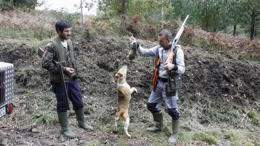 Un cazador muestra a su perro una de las piezas. // C.Giménez