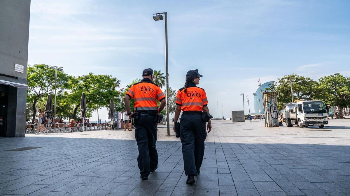 Dos agentes cívicos caminan por la Plça del Mar