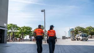 Dos agents cívics caminen por la Plaça del Mar.